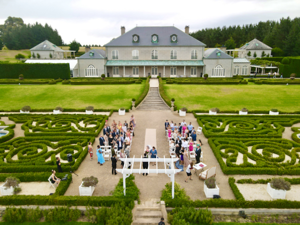 Wide angle shot of beautiful gardens and wedding ceremony taking place